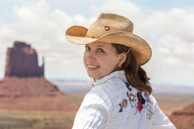 Portrait of smiling young woman standing against sky