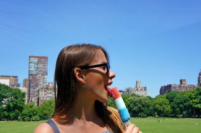 Young woman eating flavored ice in city during sunny day