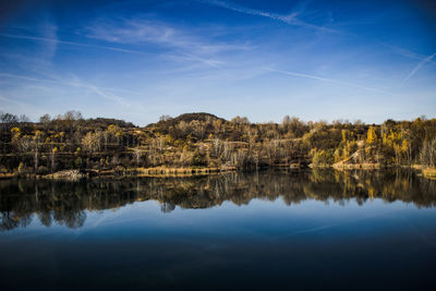 Scenic view of lake by buildings against blue sky