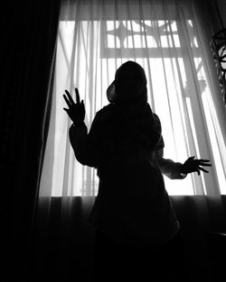 Low angle view of silhouette woman standing by window at home