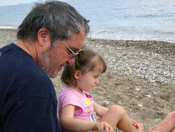 Father and daughter sitting at beach