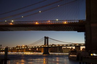 Illuminated manhattan bridge over east river in city against clear blue sky at dusk