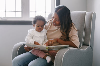 Mother and daughter sitting on sofa