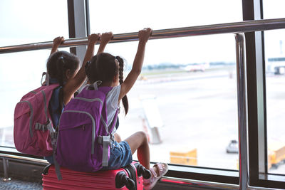 Rear view of siblings sitting at airport