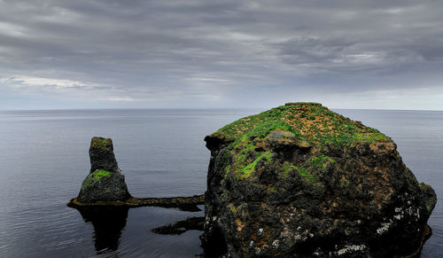 Scenic view of rocks by sea against sky