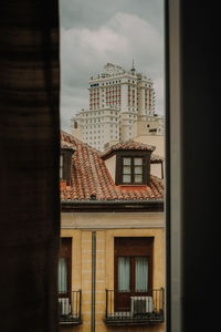 Buildings against sky seen through glass window