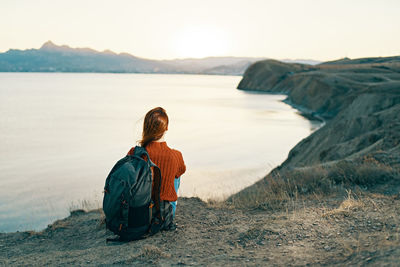 Rear view of woman sitting on beach