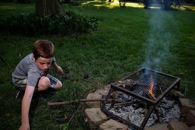 Young man relaxing on barbecue grill in yard