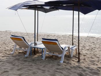 Empty chairs on beach by sea