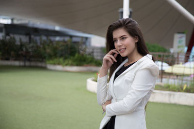 Young woman using mobile phone while standing on camera