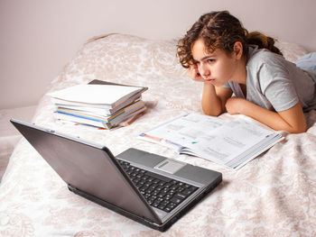 Teenager girl studying while lying on bed