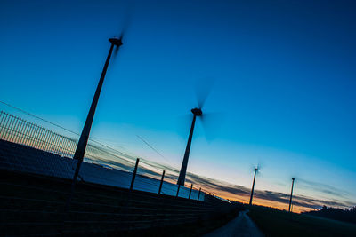 Low angle view of telephone pole against clear blue sky