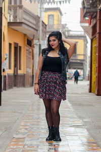 Portrait of woman standing on footpath in city