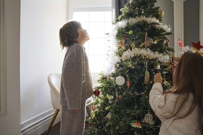 Boy with girl decorating christmas tree at home
