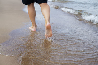 Low section of man walking on beach