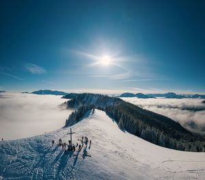 Panoramic view of people skiing on snowcapped mountain against sky