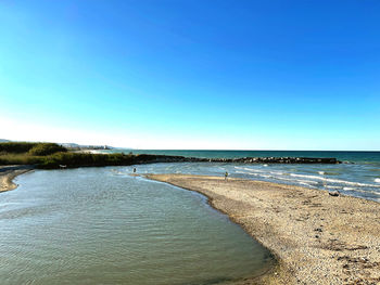 Scenic view of beach against clear blue sky