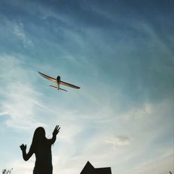 Low angle view of silhouette man flying against sky