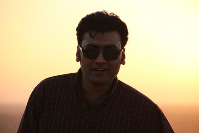 Portrait of man wearing sunglasses against sky during sunset