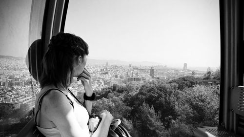 Rear view of woman looking through window