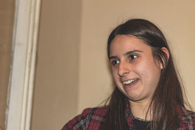 Portrait of smiling young woman against wall at home