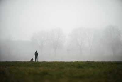 Rear view of man on field against sky