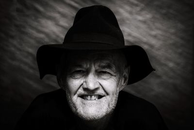 Portrait of smiling man wearing hat against wall