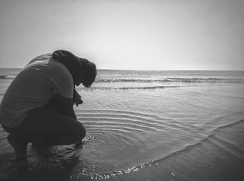 Man wearing sunglasses on beach against sky