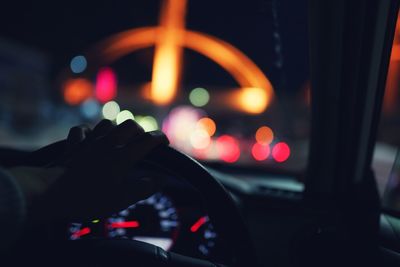 Cropped hand of person driving car at night