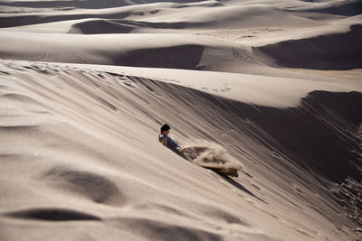 Boy sliding on sandy slope