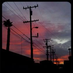 Low angle view of electricity pylon against cloudy sky