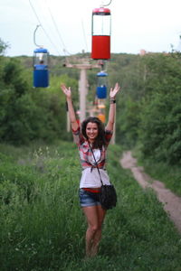 Portrait of woman walking under overhead cable cars on field