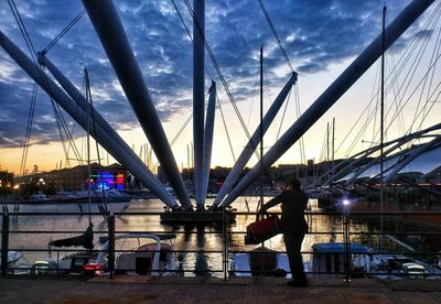 People walking on bridge against cloudy sky