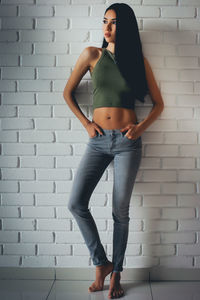 Full length portrait of woman standing against wall