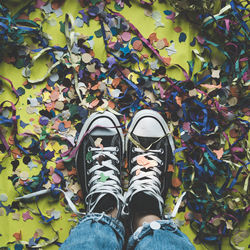 Feet seen from above on a floor full of colorful confetti