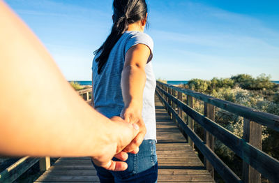 Low angle view of woman on footbridge against sky