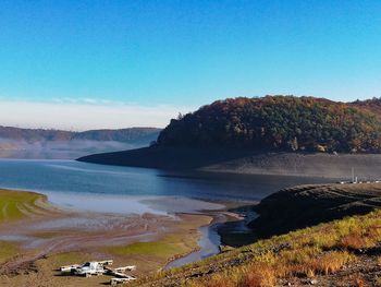 Scenic view of sea and mountains against clear blue sky