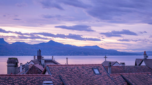 Scenic view of sea and buildings against sky during sunset