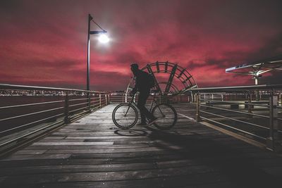 Man cycling on bridge in city at night