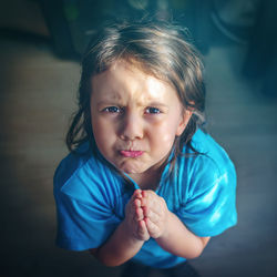 Portrait of cute girl begging with hands clasped at home