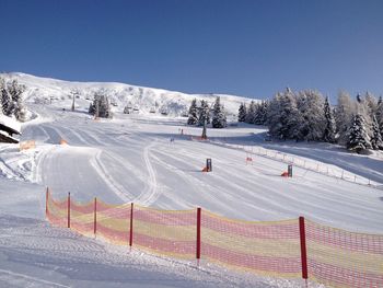 Snow covered land and mountains against clear sky