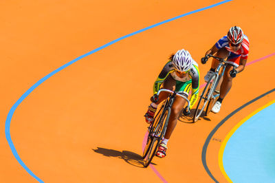 Man riding bicycle on umbrella against orange wall