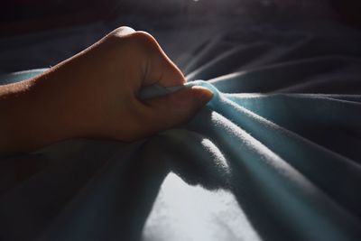 Close-up of person hand on bed