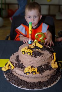 Little toddler sitting at the table in front of his birthday cake