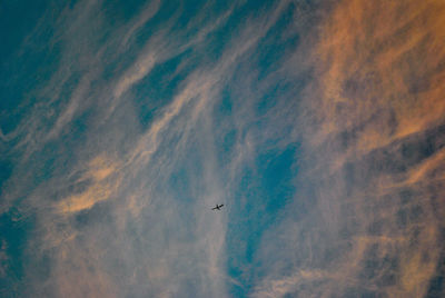 Low angle view of airplane flying against cloudy sky