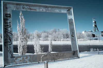 Frozen trees against clear sky seen through window