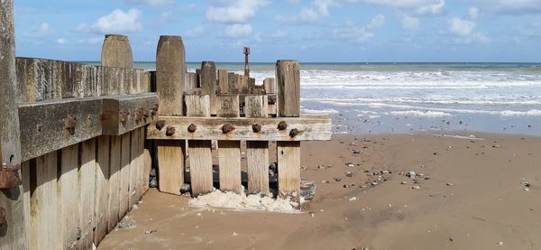 Wooden posts on beach against sky