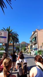 Rear view of people walking against blue sky