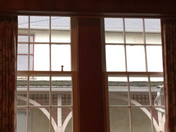 Close-up of built structure against sky seen through window