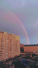 Rainbow over buildings in city against sky